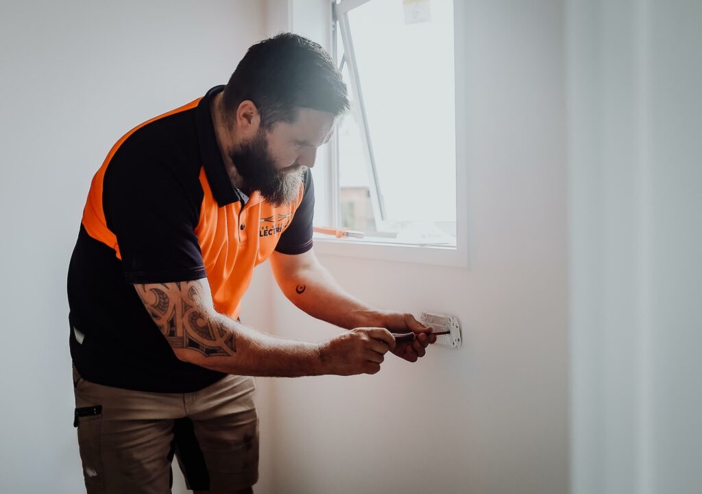 A man fixing a light switch in a room.
