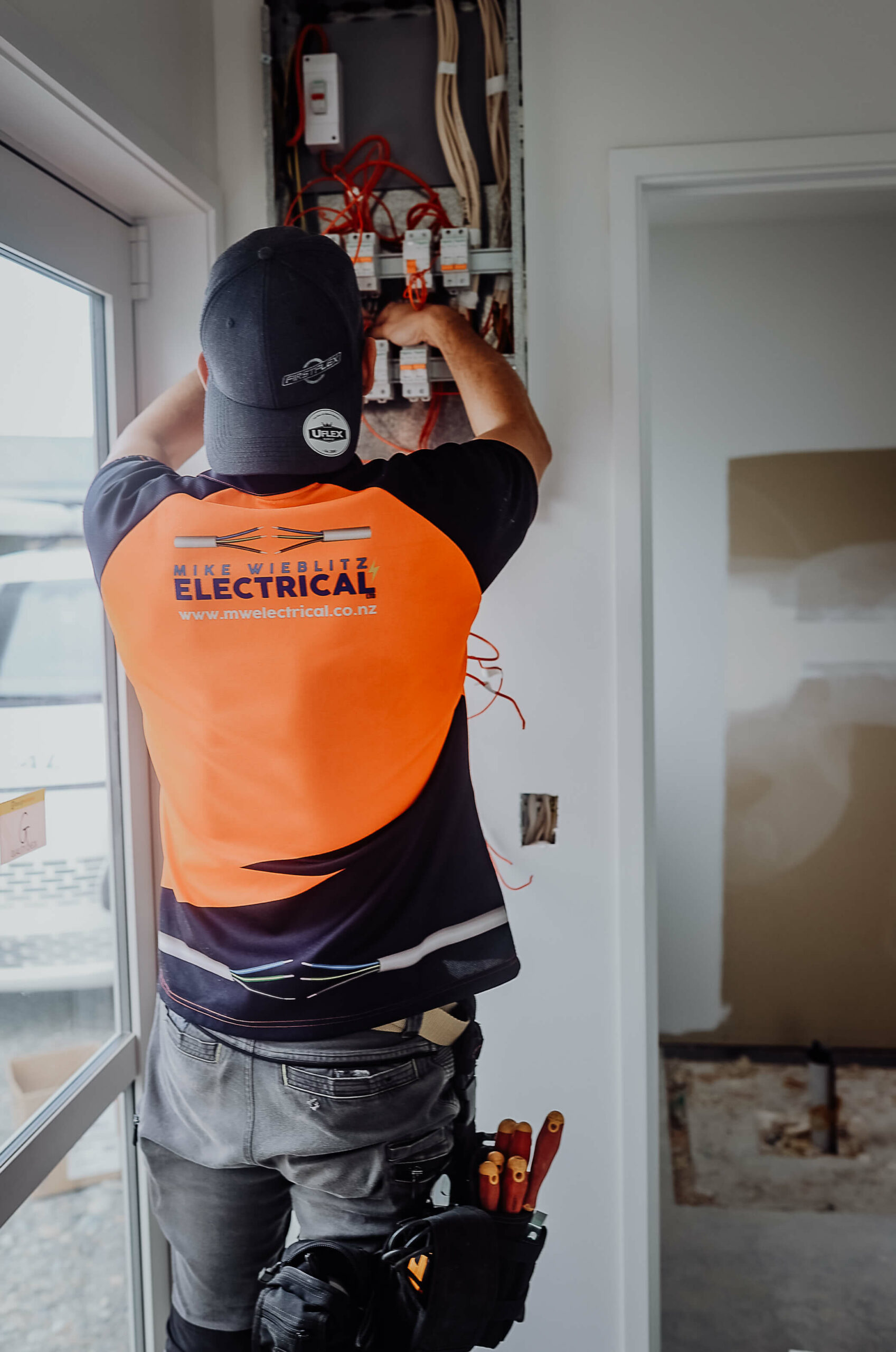 A man working on an electrical panel in a house.